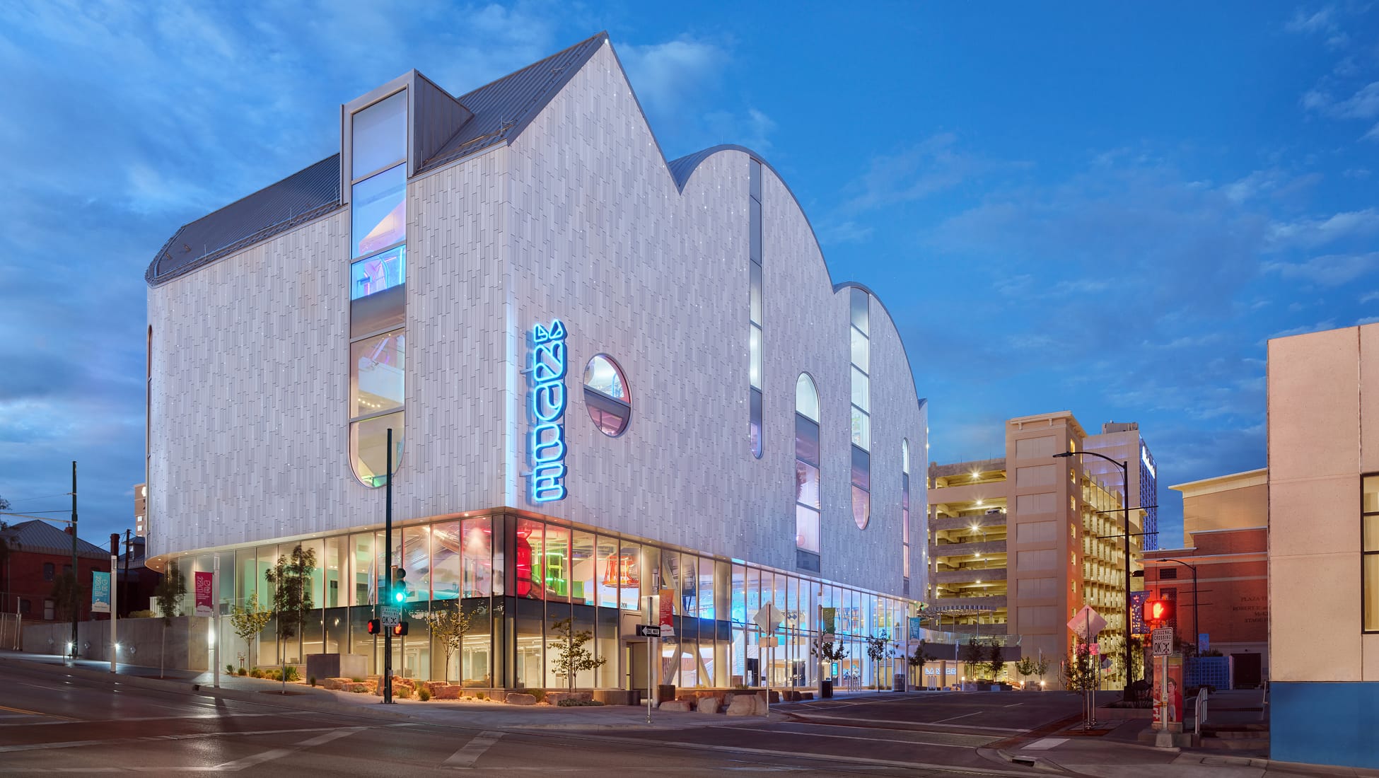 La Nube children's museum exterior at dusk with illuminated vertical neon signage — environmental graphic design by RSM Design