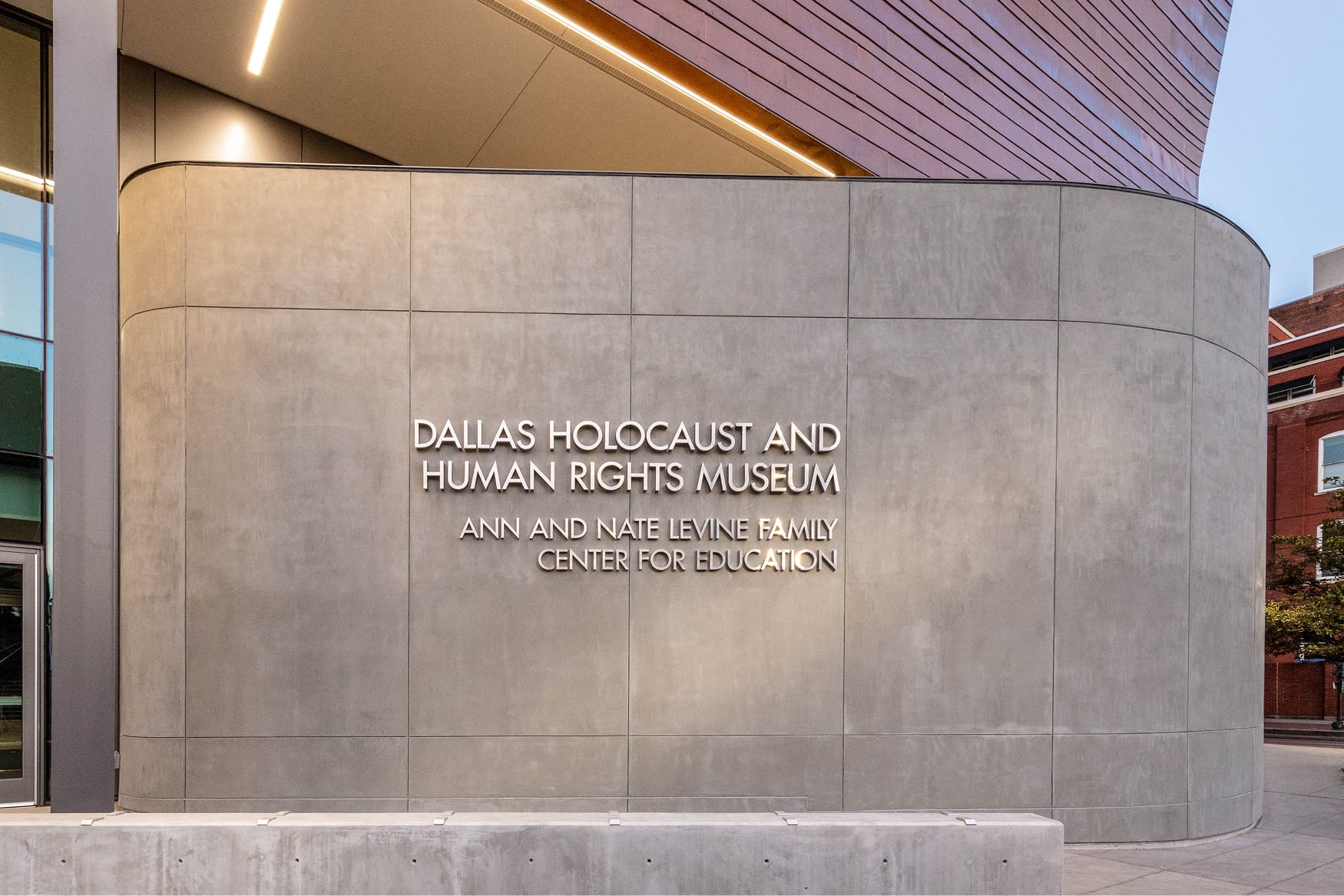 Illuminated dimensional letter signage for Dallas Holocaust and Human Rights Museum on curved concrete facade - donor recognition and identity design by RSM Design