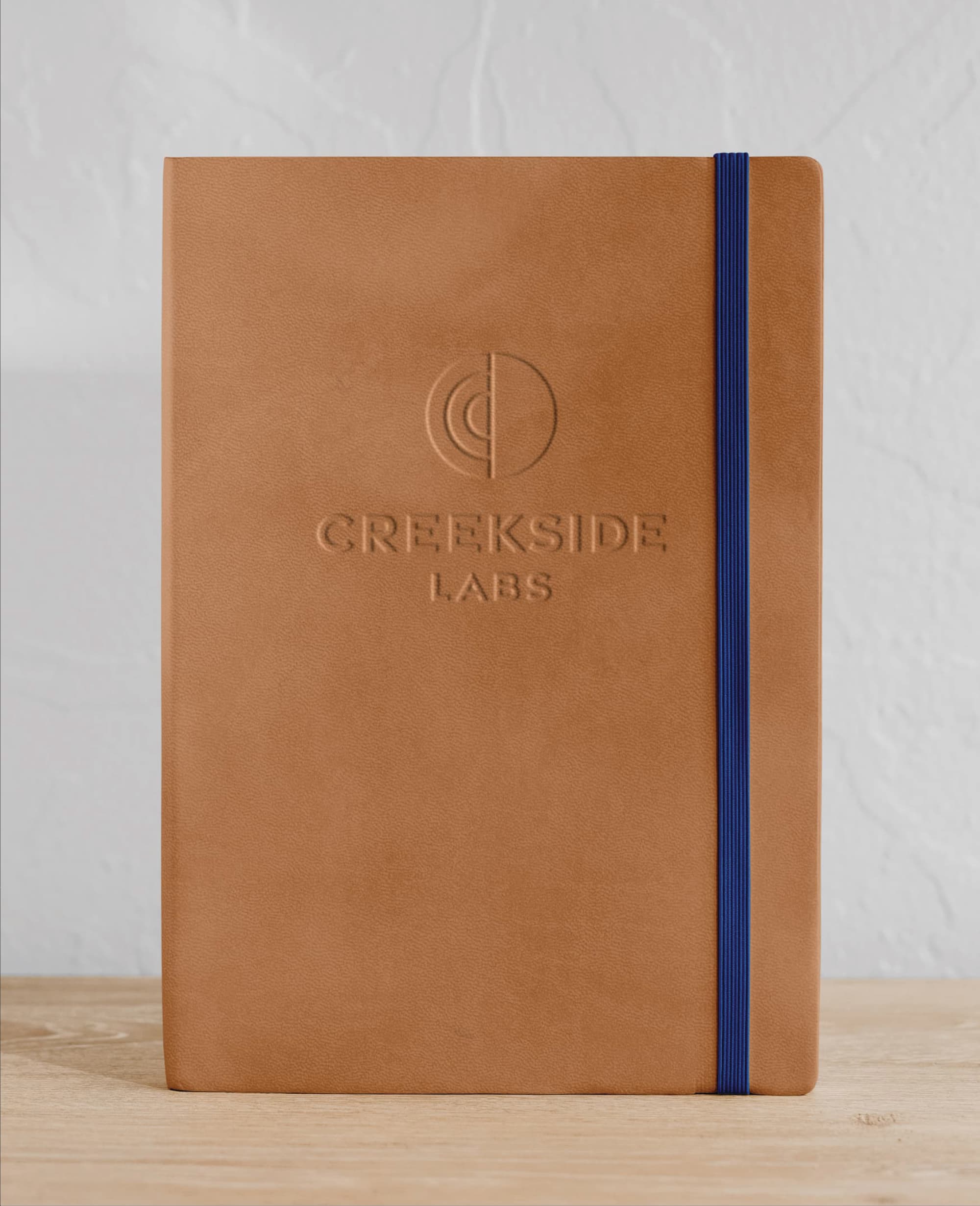 Embossed Creekside Labs branded notebook showcasing visual identity design and brand development for a life science campus, illustrating environmental graphic design and placemaking strategy for workplace and innovation district environments.