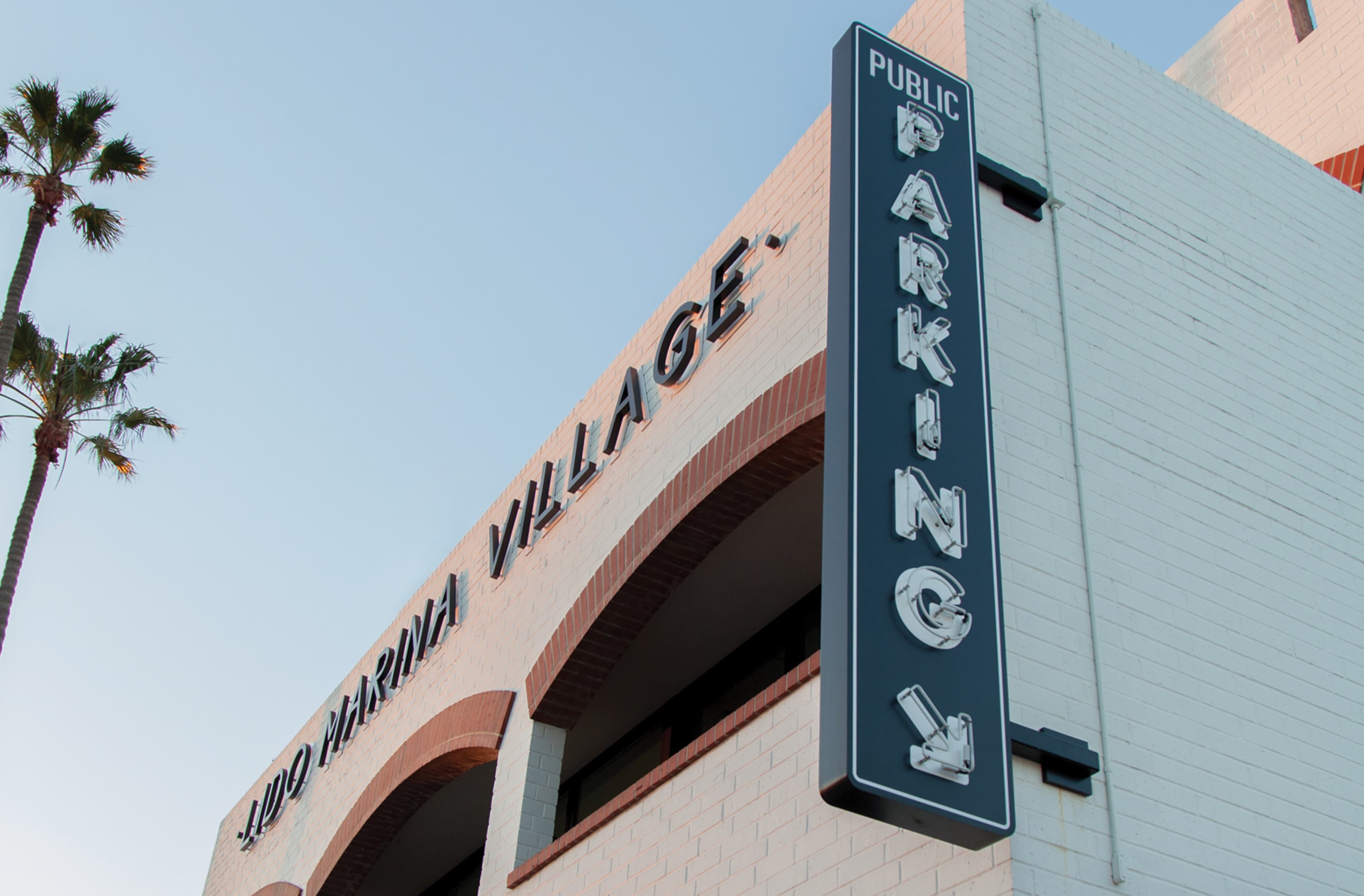 Image of the outside of the parking garage at Lido Marina Village. Public Parking directional sign with neon lettering, designed by RSM Design. 