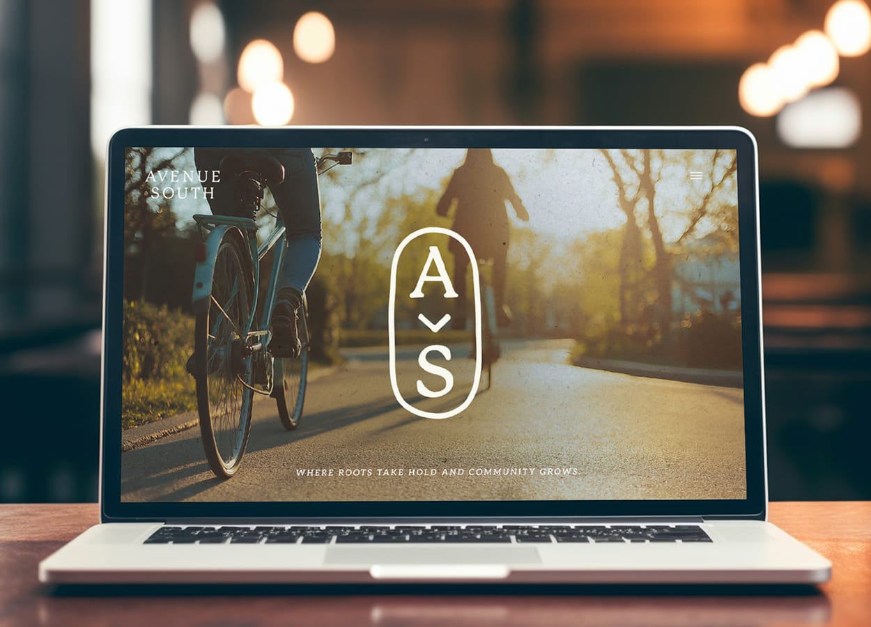 Laptop displaying Avenue South website homepage with cyclist on tree-lined path and monogram logo, brand identity website design by RSM Design.