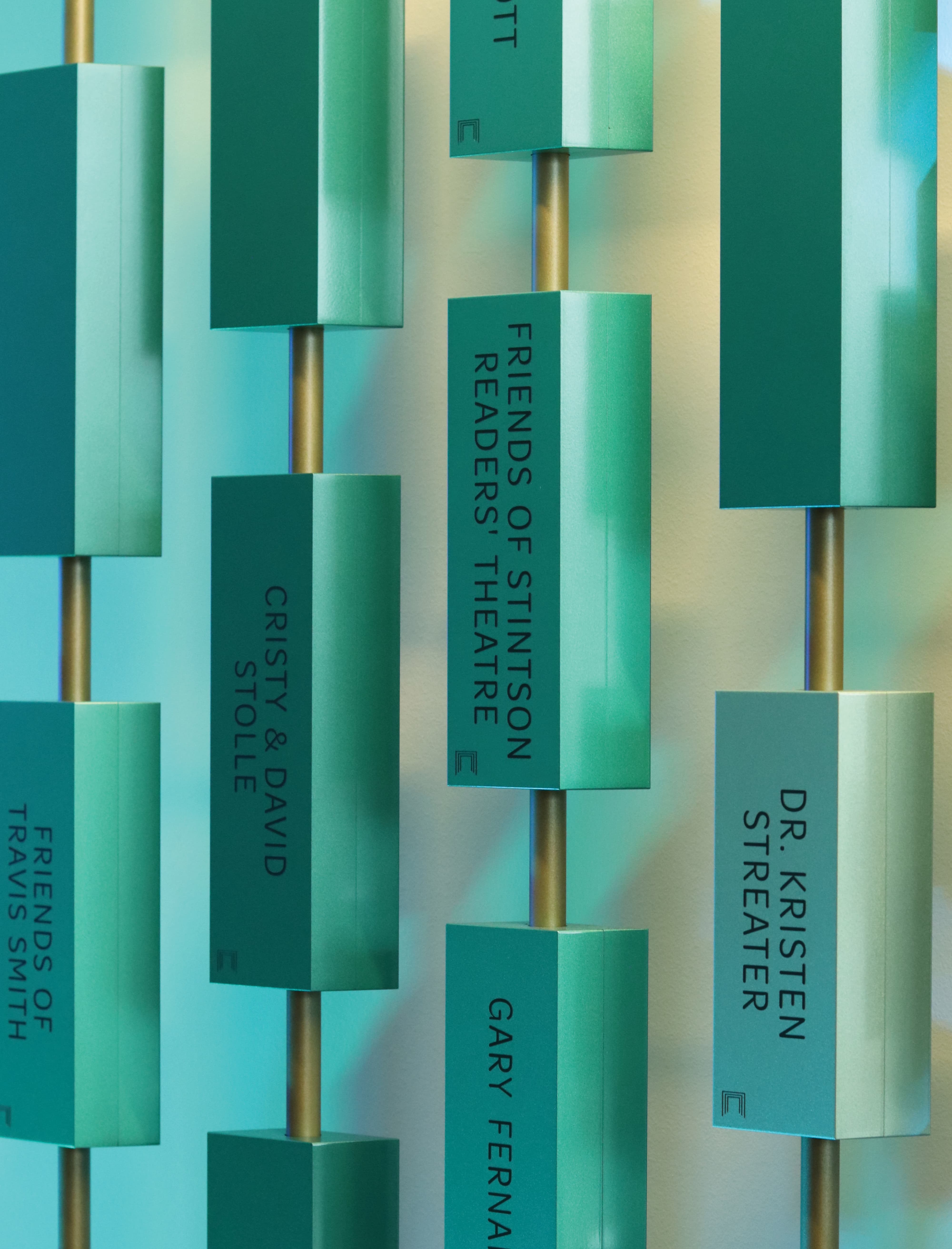 Close-up of a sculptural donor recognition installation with dimensional plaques and engraved donor names, highlighting environmental graphic design, experiential storytelling, and placemaking within higher education and performing arts environments.