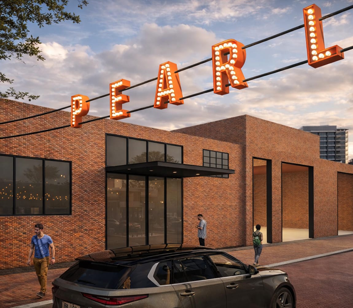 Illuminated “Pearl” marquee sign suspended above a brick building in San Antonio’s Pearl District, featuring adaptive reuse architecture, pedestrian streetscape, and branded environmental graphic design.