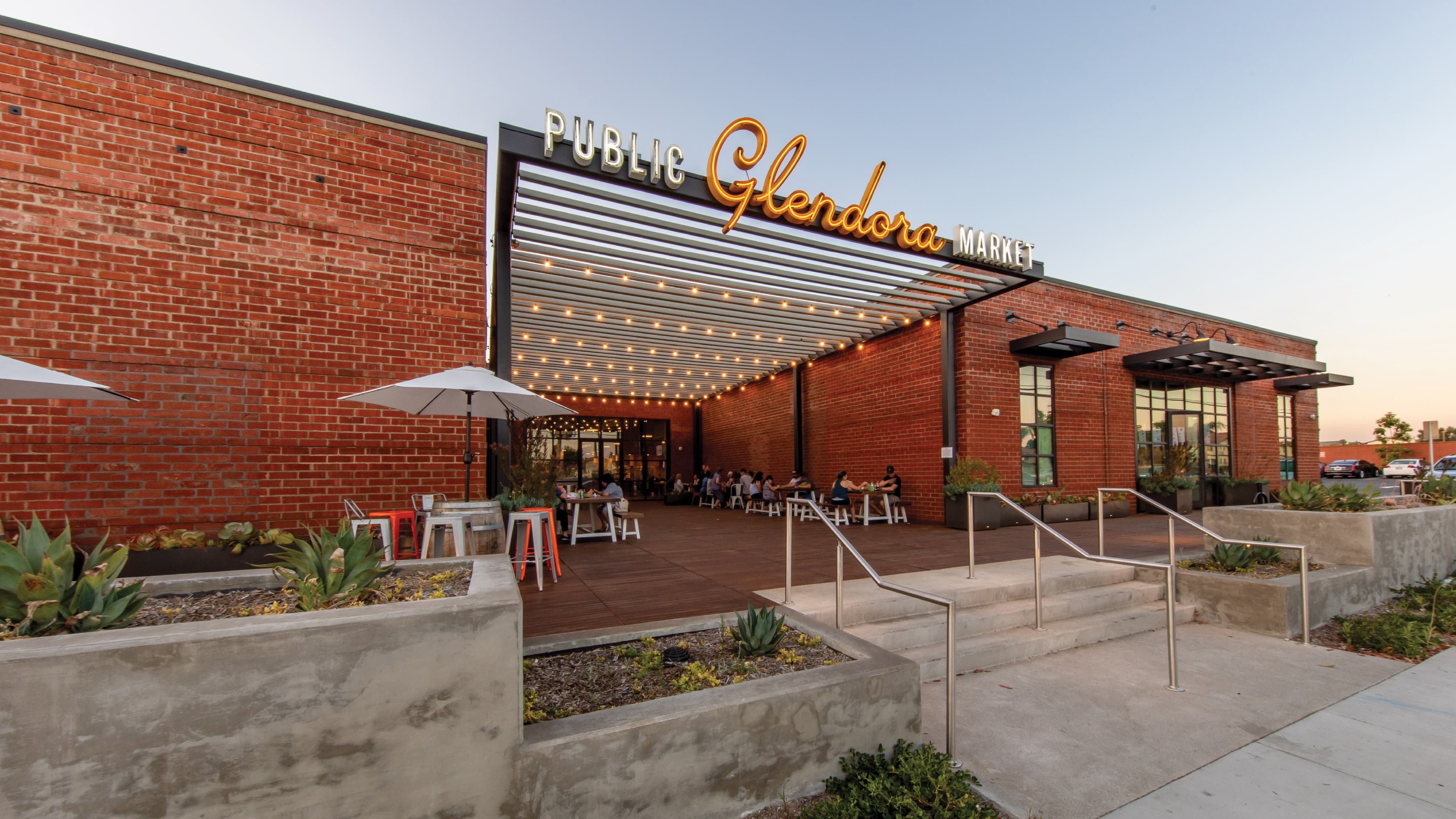 Public Glendora Market exterior with branded signage, outdoor dining, and integrated environmental graphic design, highlighting placemaking, identity, and wayfinding for a retail and hospitality mixed-use destination by RSM Design