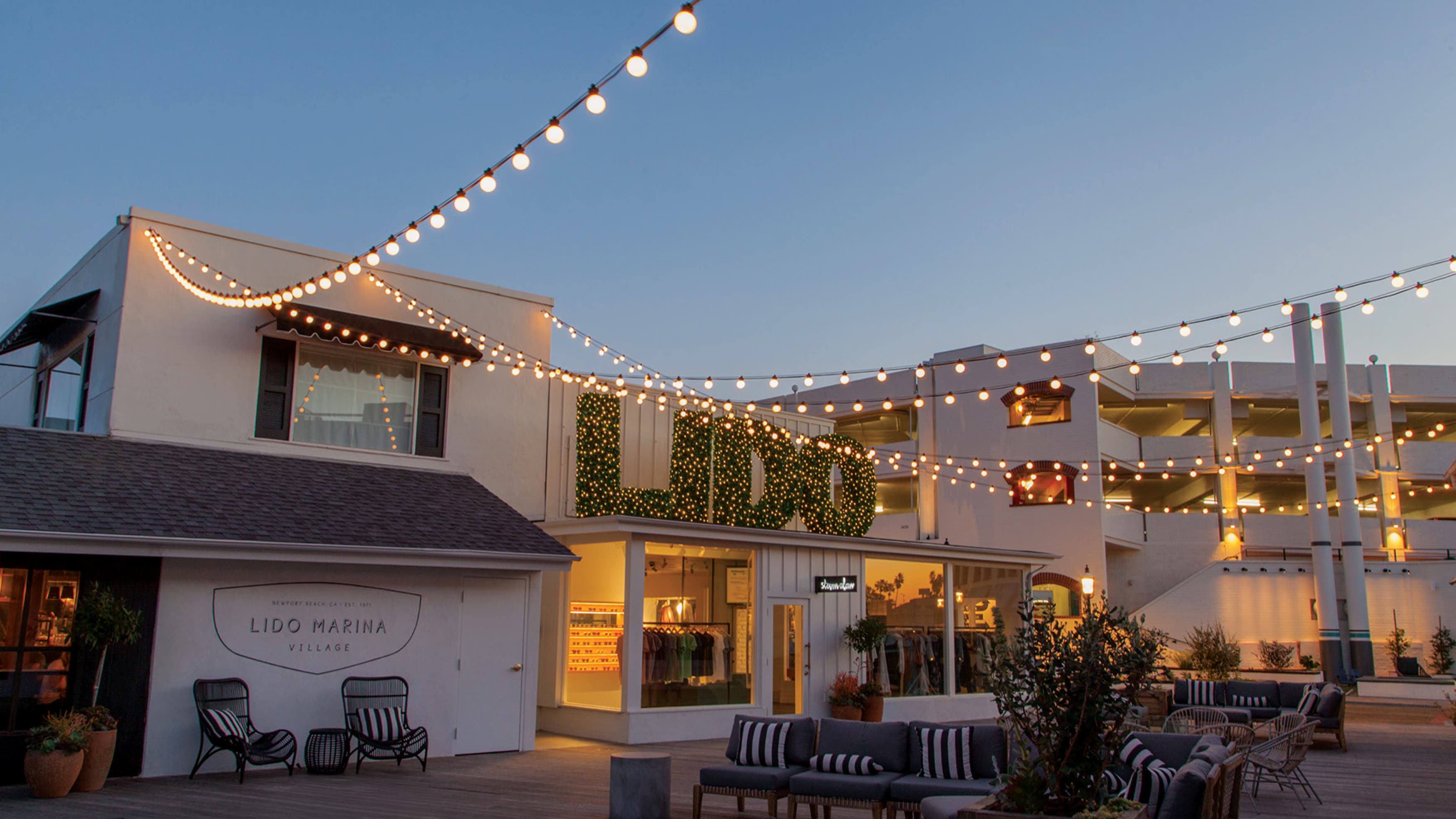 Image of the plaza of Lido Marina village at dusk with lights. Environmental graphic design by RSM Design. 