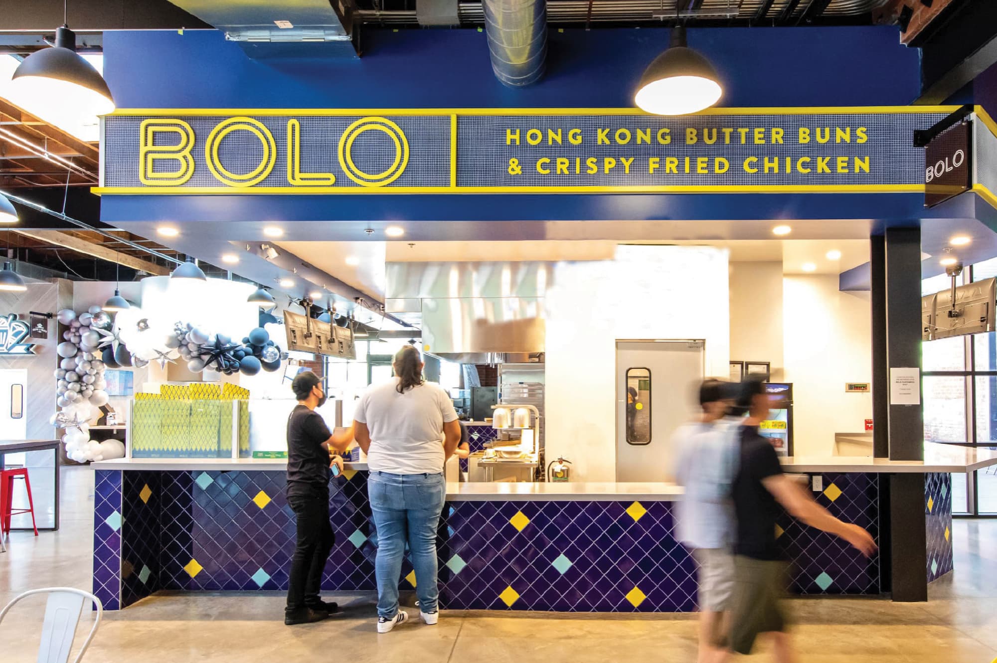 BOLO food stall at a public market featuring branded environmental graphics, identity signage, and wayfinding within a retail and hospitality mixed-use destination, enhancing the guest experience through RSM Design’s experiential design approach