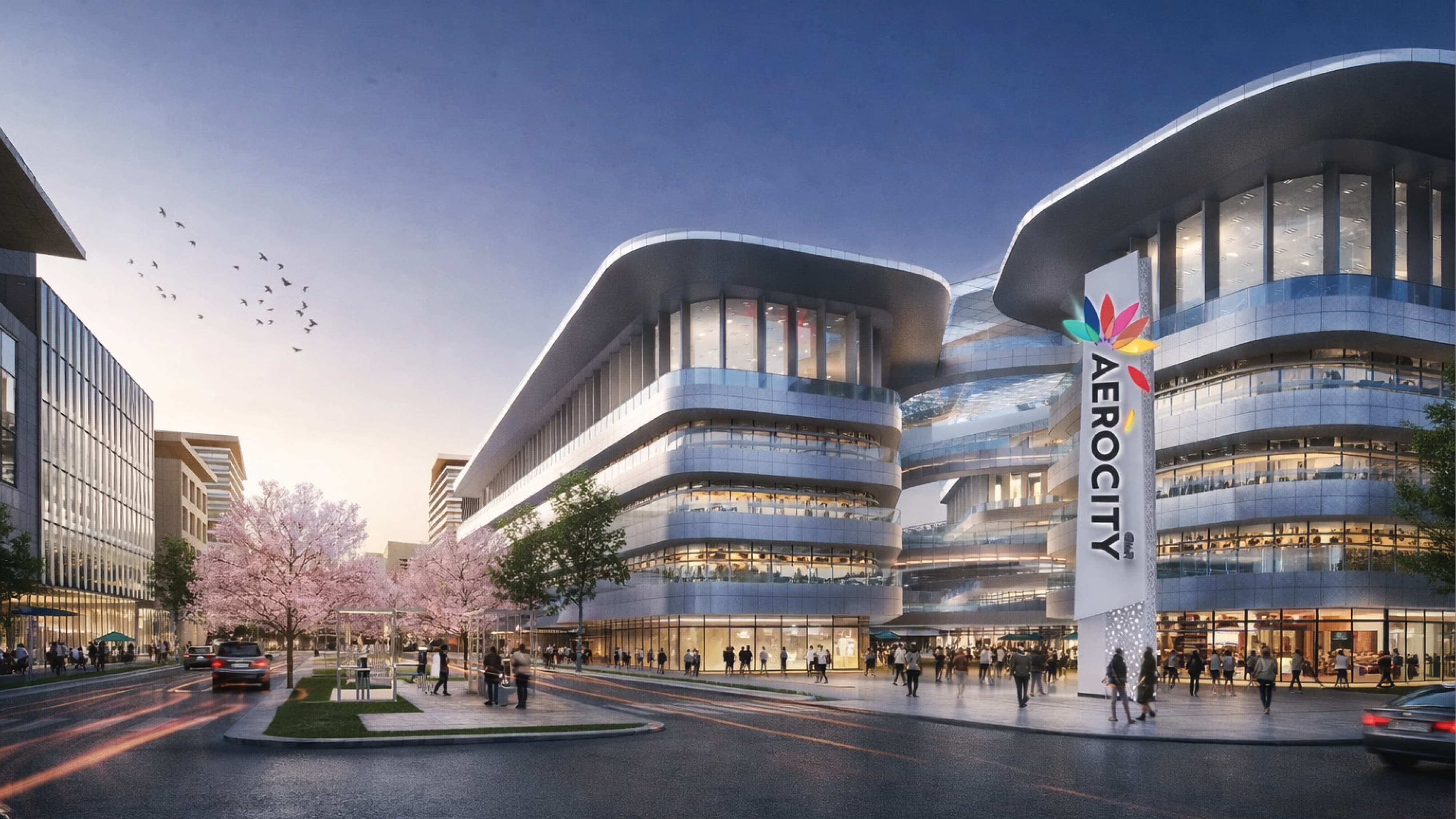 Architectural rendering of Aerocity international mixed-use destination at dusk featuring a large-scale branded pylon monument sign with colorful lotus flower logo, activated pedestrian streetscape, and sweeping multi-level curved building facade — RSM Design branding and visual identity, wayfinding and signage design, master sign programs, experiential placemaking, and environmental graphic design for mixed-use, retail, transit, streetscape, and international destinations.