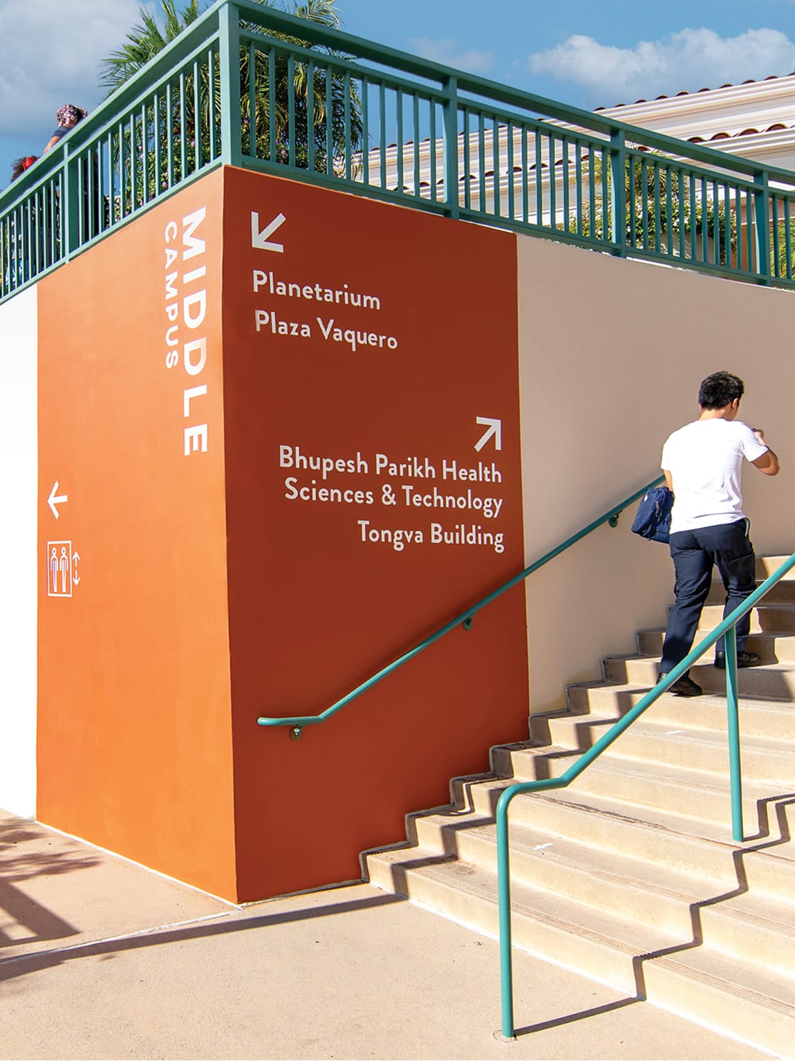 Large-scale environmental wayfinding wall graphic at Glendale Community College Middle Campus designed by RSM Design, directing students to the Planetarium, Plaza Vaquero, and Parikh Health Sciences and Technology building at a staircase junction