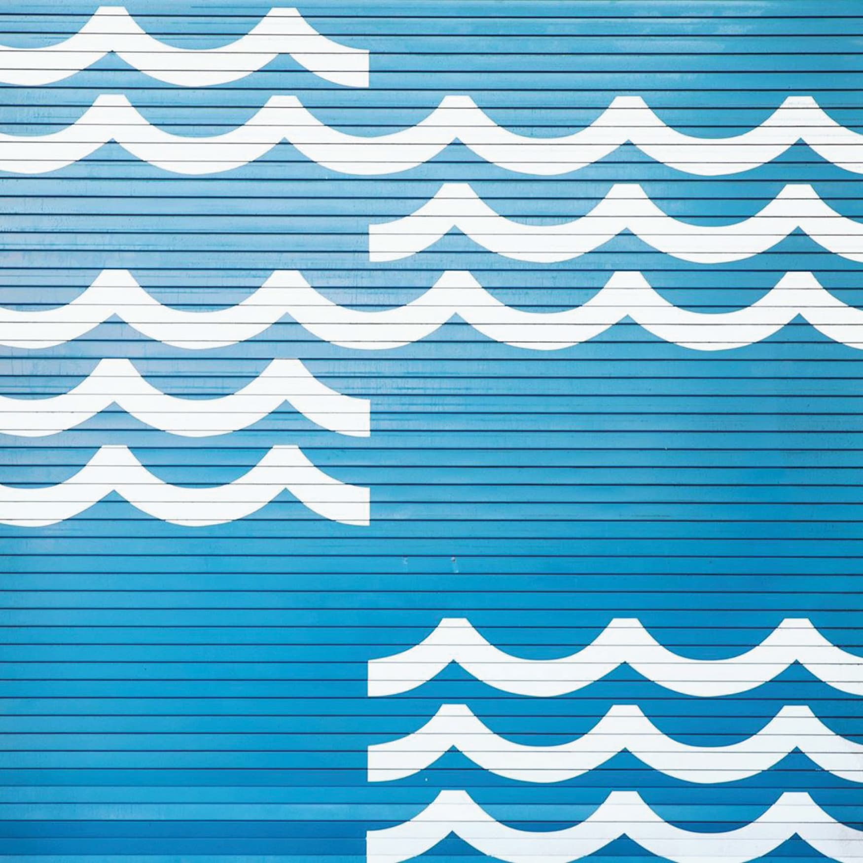 Image of blue wall mural with playful waves, designed by RSM Design. 