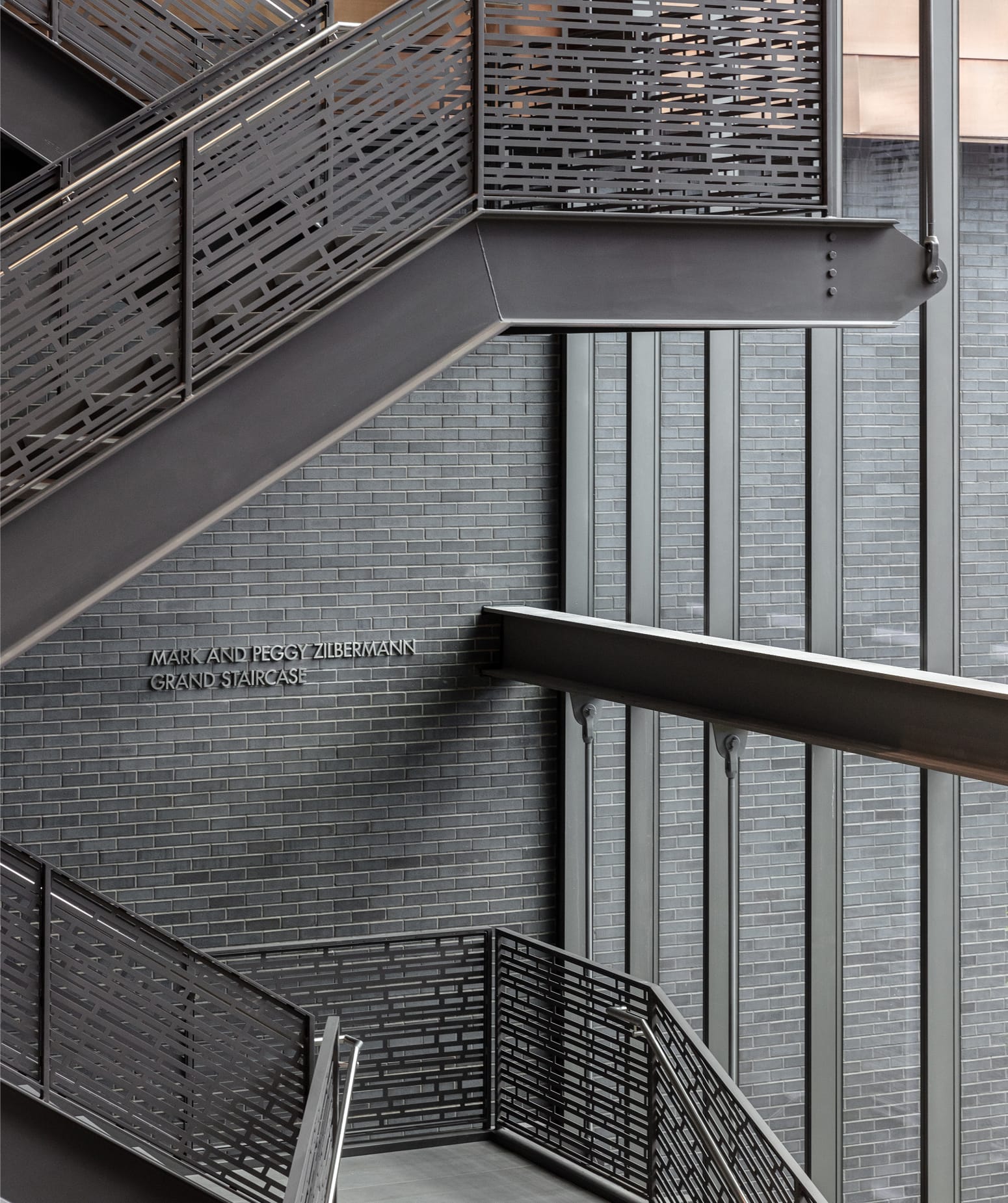 Grand staircase donor wall signage with perforated metal railings at Dallas Holocaust and Human Rights Museum - environmental graphic design by RSM Design