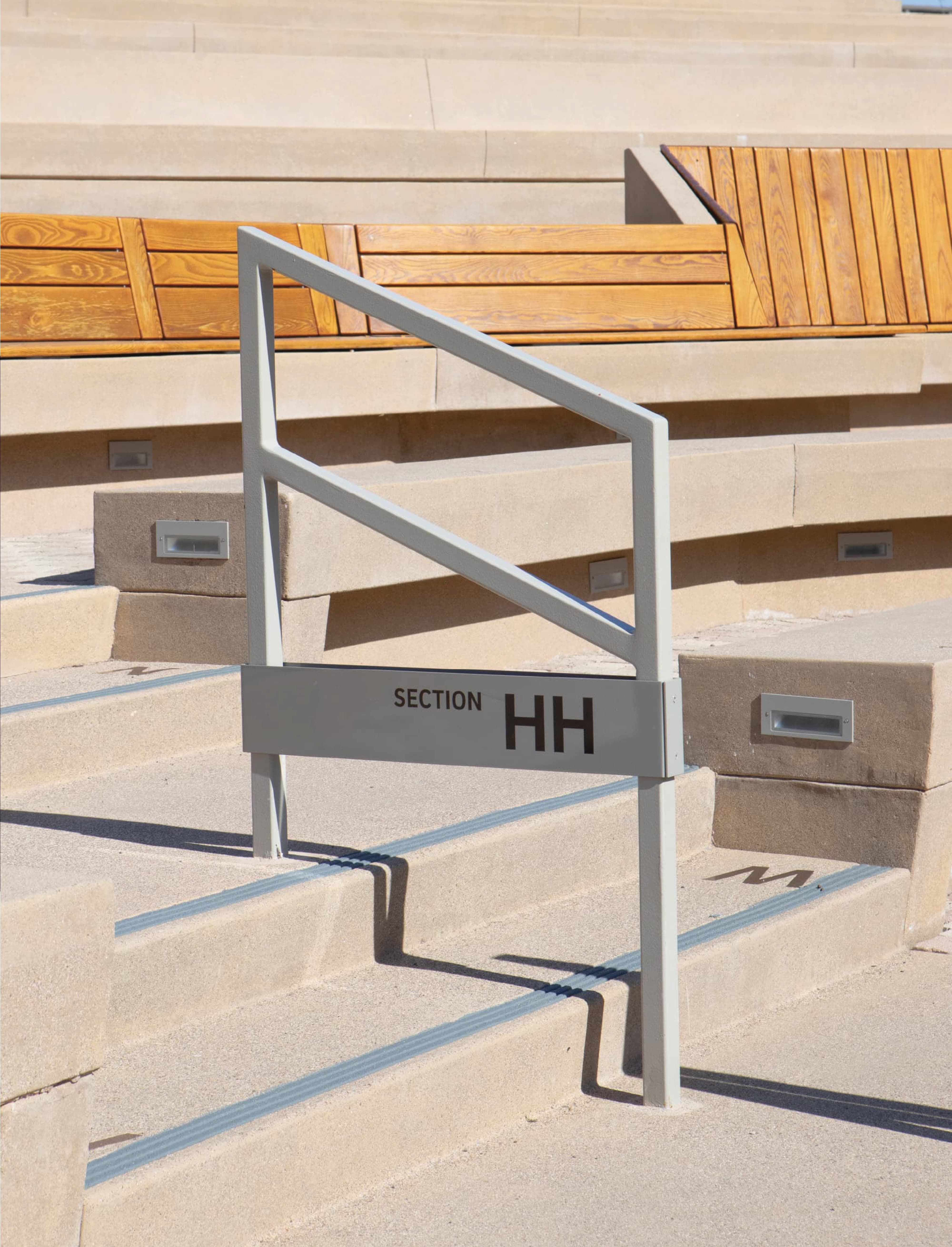 Amphitheater wayfinding signage marking “Section HH” integrated into stair handrail, demonstrating environmental graphic design, signage systems, and user navigation within a public gathering space and mixed-use campus by RSM Design