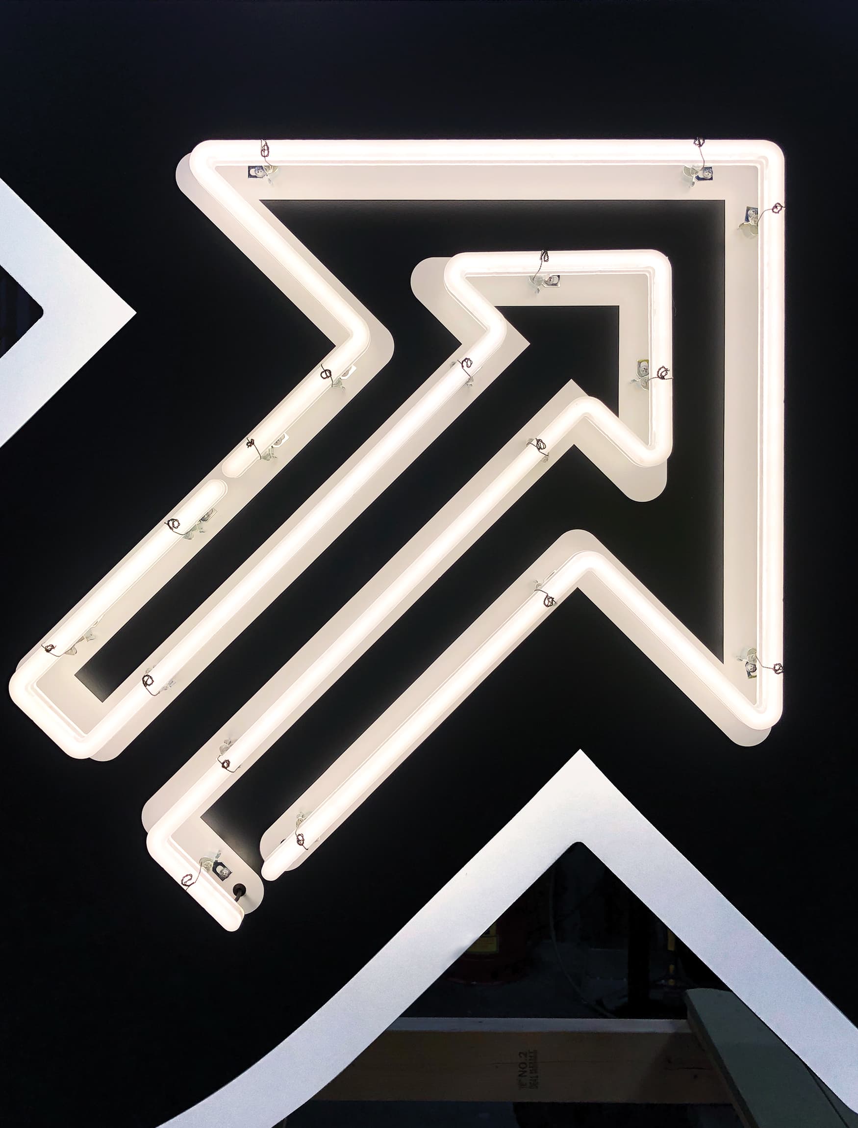 Detail image of the white arrow graphic with neon tubing on the Parking blade sign. Signage and wayfinding for Fifth + Broadway in Nashville, Tennessee by RSM Design